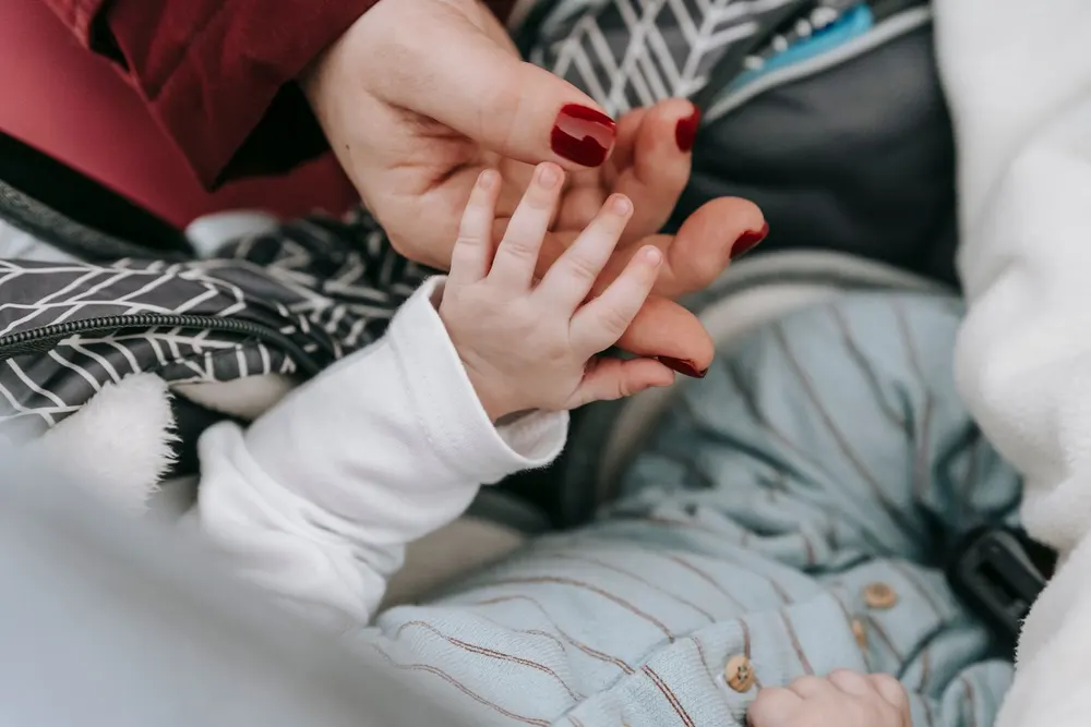 A mother holding her newborn baby's hands